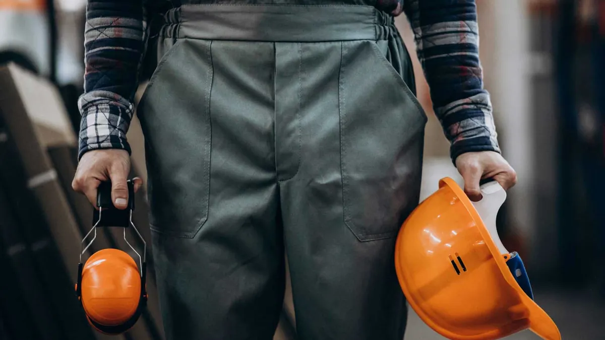 Engineer holding a hard hat and ear defenders on site
