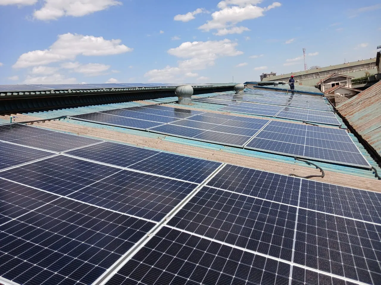 Solar PV panels on an industrial roof with a technician maintaining the array