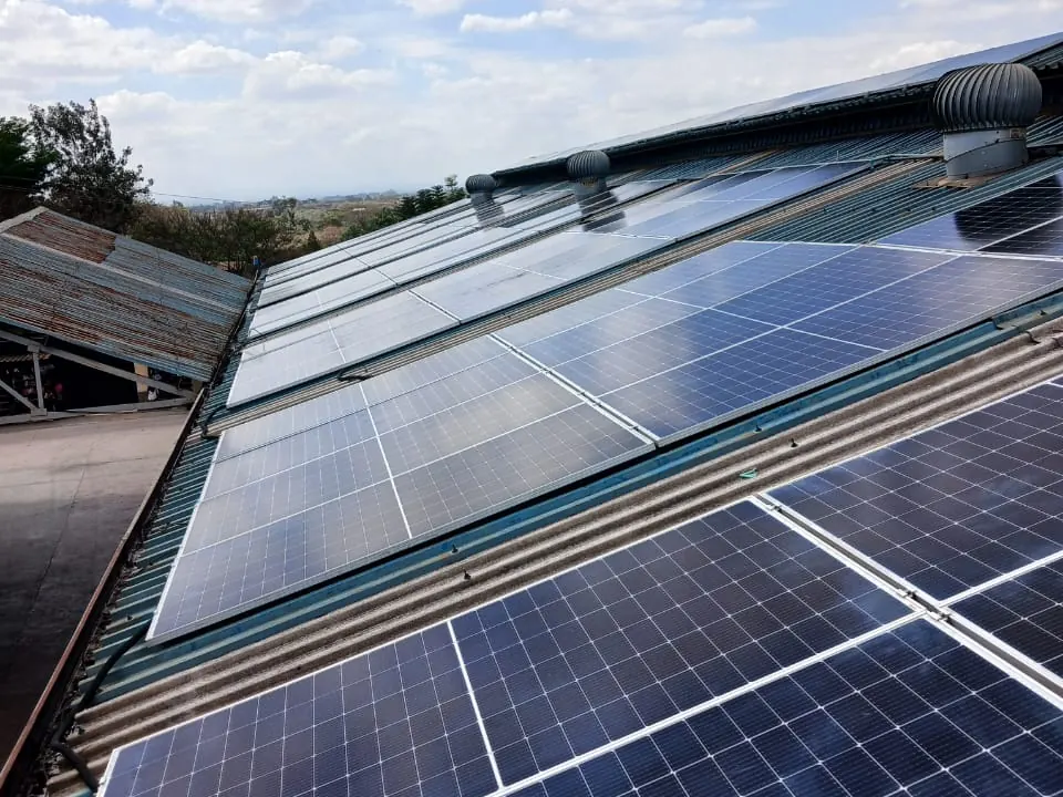 Solar PV array on a corrugated industrial roof under a blue sky